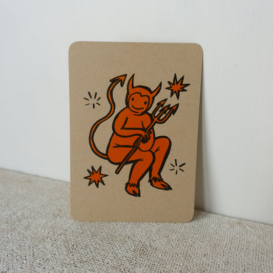 Orange and black illustration of a cartoon devil on kraft color paper with rounded corners.