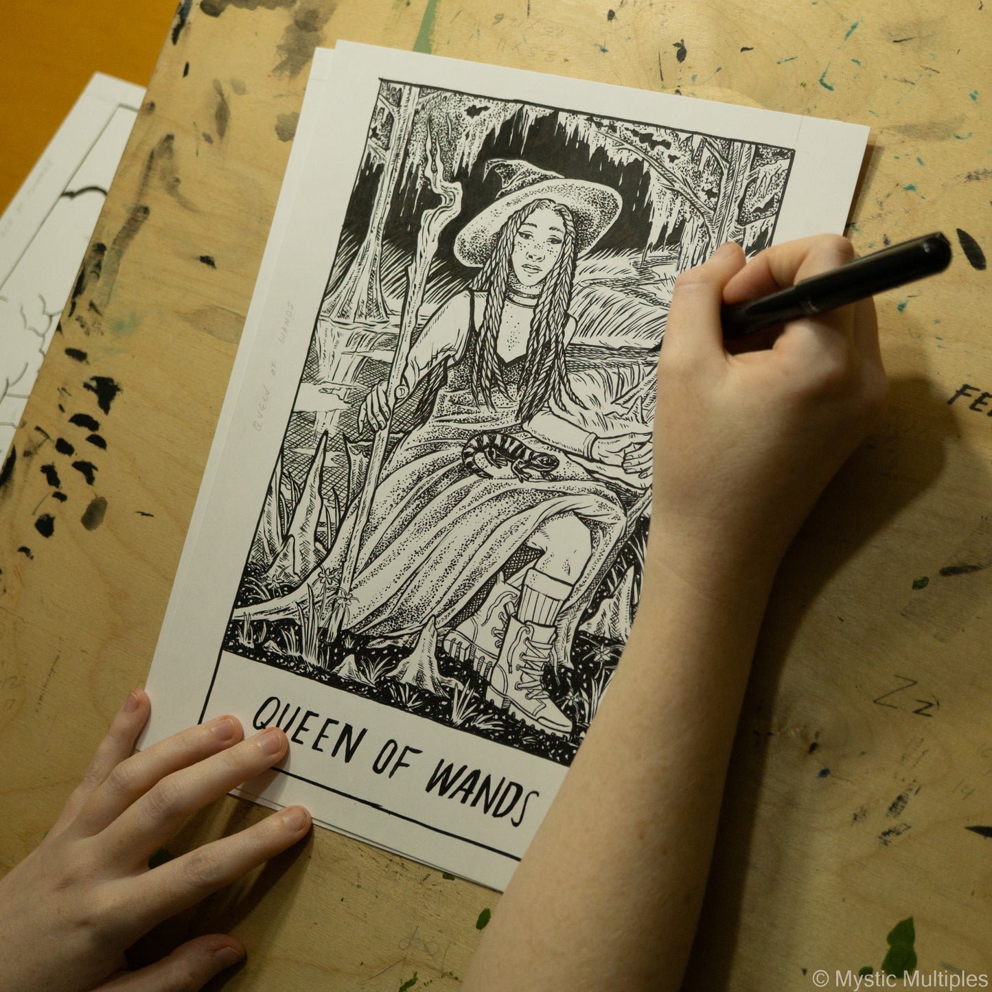 In progress shot of the queen of wands being drawn in black ink