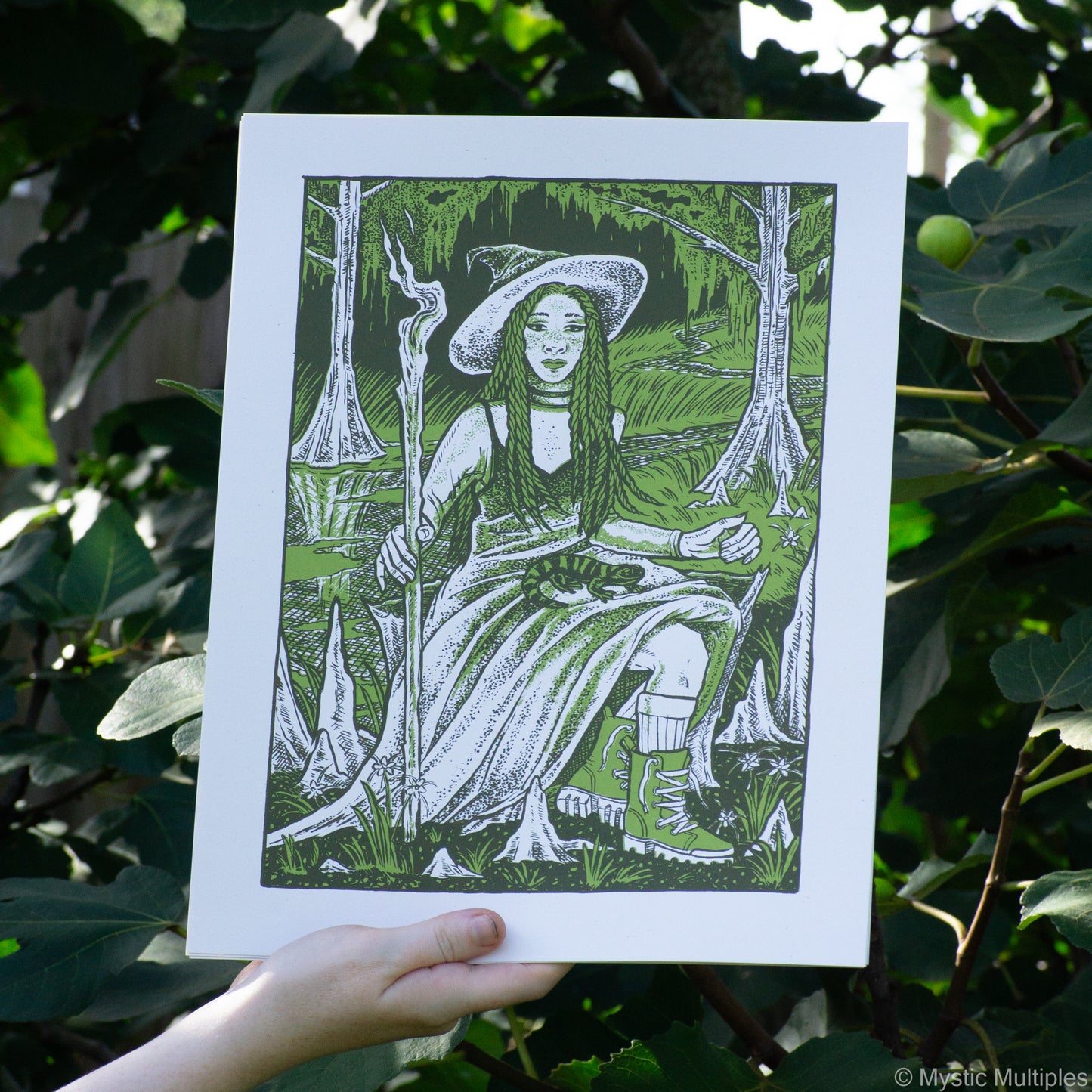 The queen of wands in her swamp with her companion fire salamander in her lap