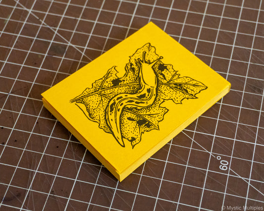 Banana slug notepad pictured on a cutting matt