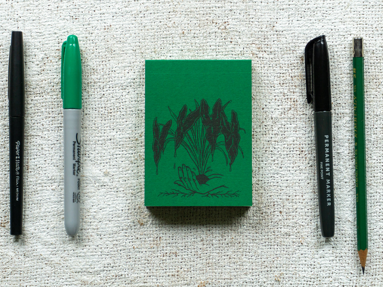 Green notebook with pens and pencils.