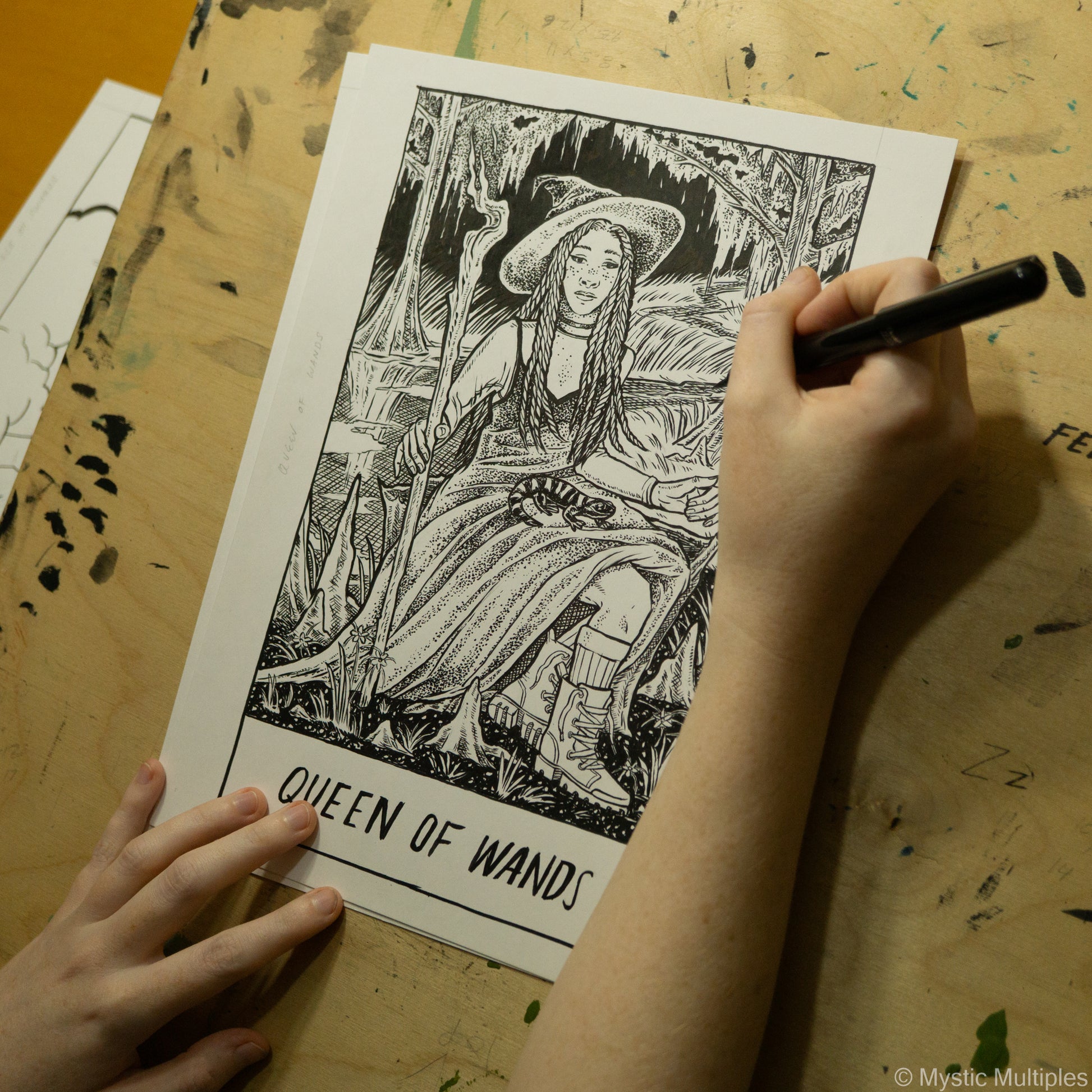 In progress shot of the queen of wands being drawn in black ink
