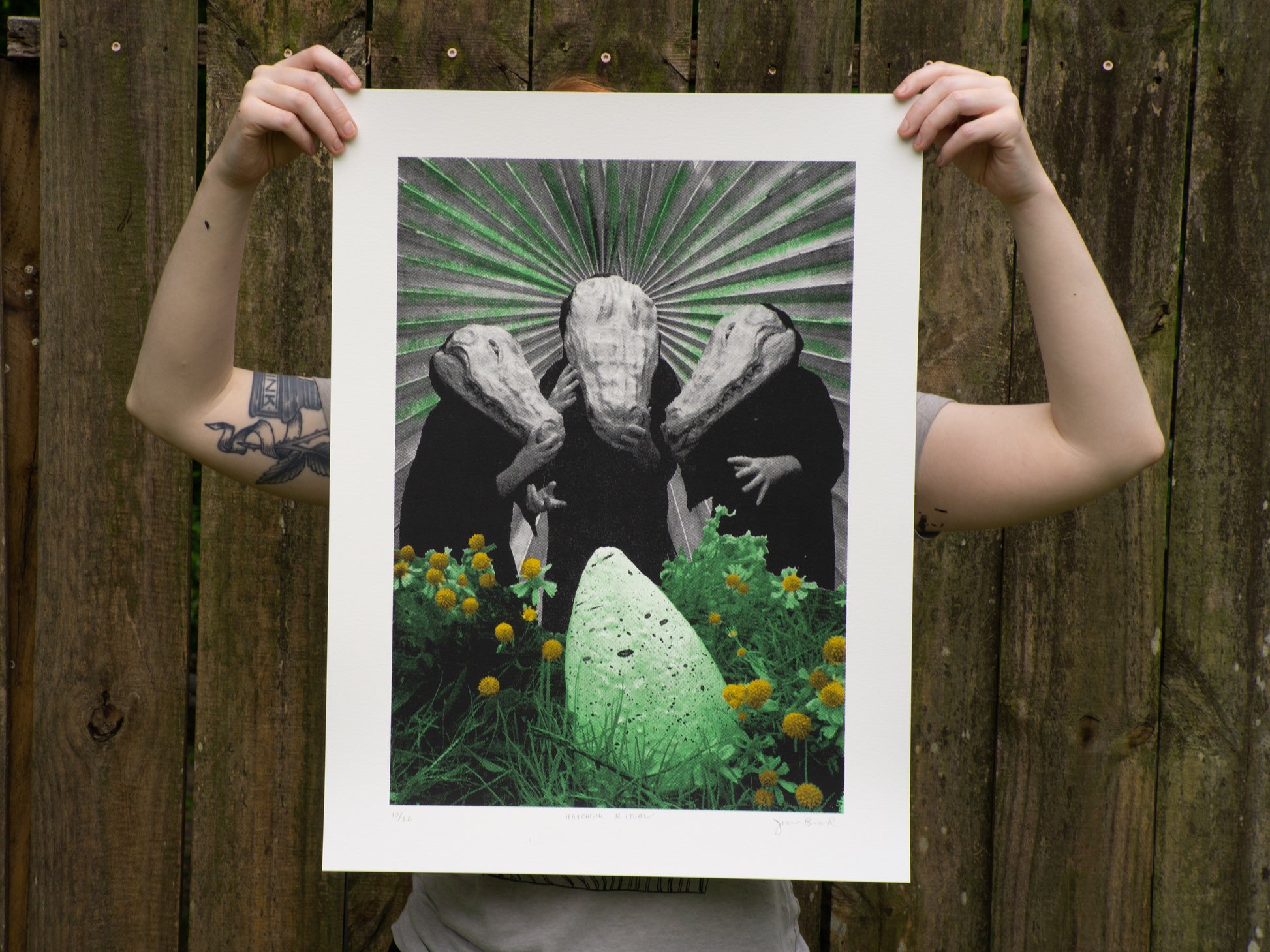 18x24 screenprint with three alligator humanoids standing over an egg. The print is held by a person for scale.