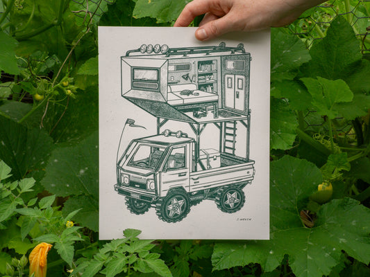 Hand holding a print with green ink of a kei truck with an apartment on top of it.