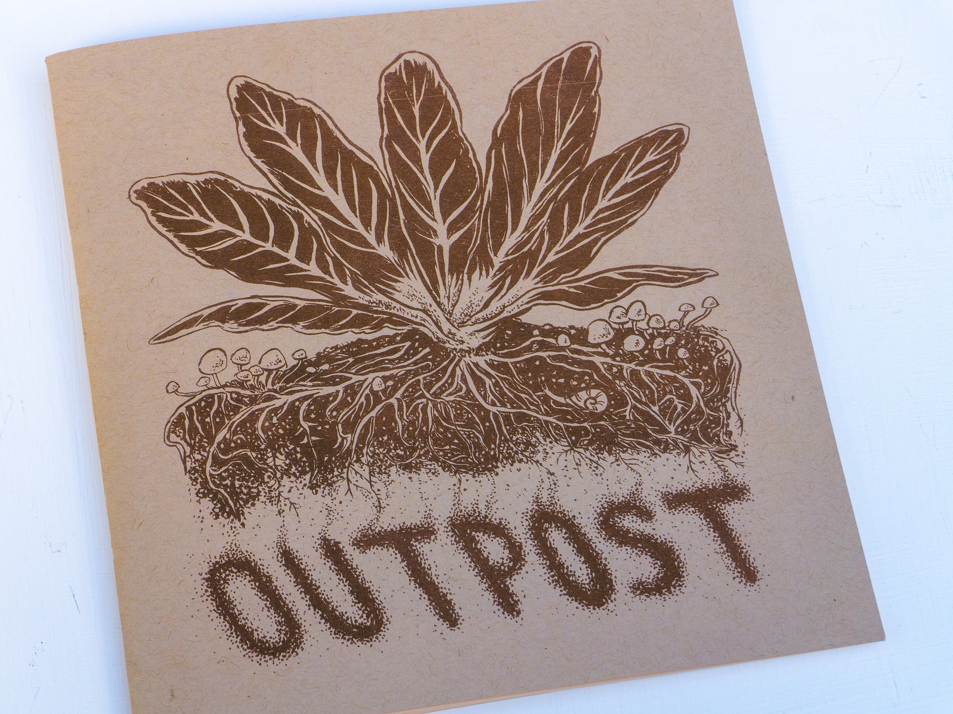 Cover of the zine with a mustard plant growing among mushrooms with an underground view of the root structure.